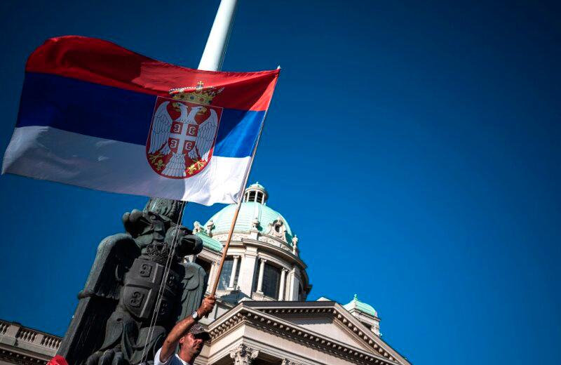 A man holds the Serbian national flag during a protest in front of the National assembly building in Belgrade on June 18, 2020. AFPPIX