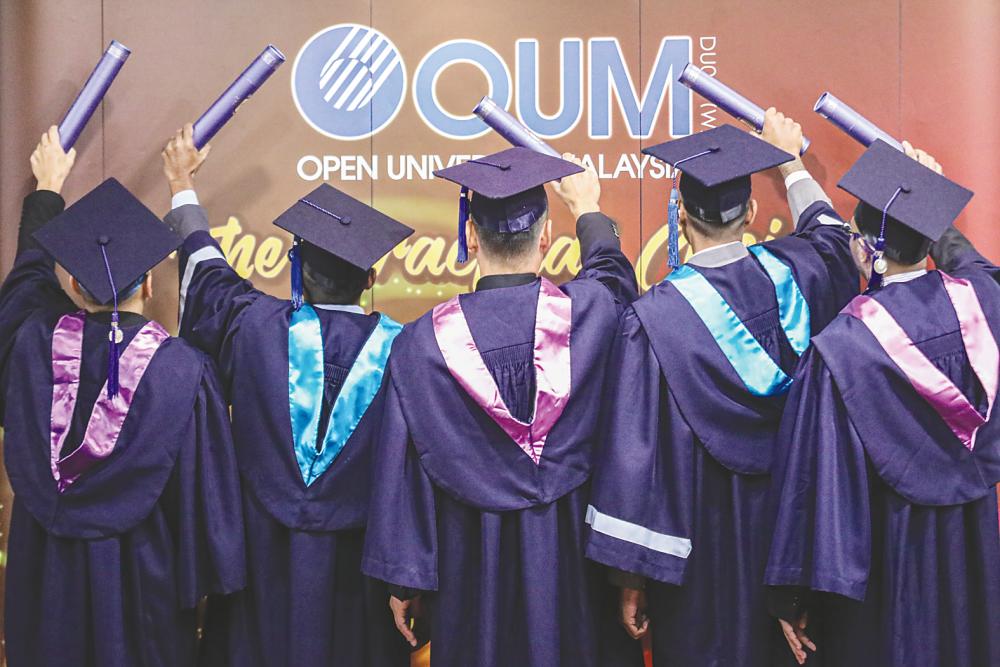The five inmates from Kajang Prison hold their scrolls high at the OUM convocation on Sunday. – AMIRUL SYAFIQ/THESUN