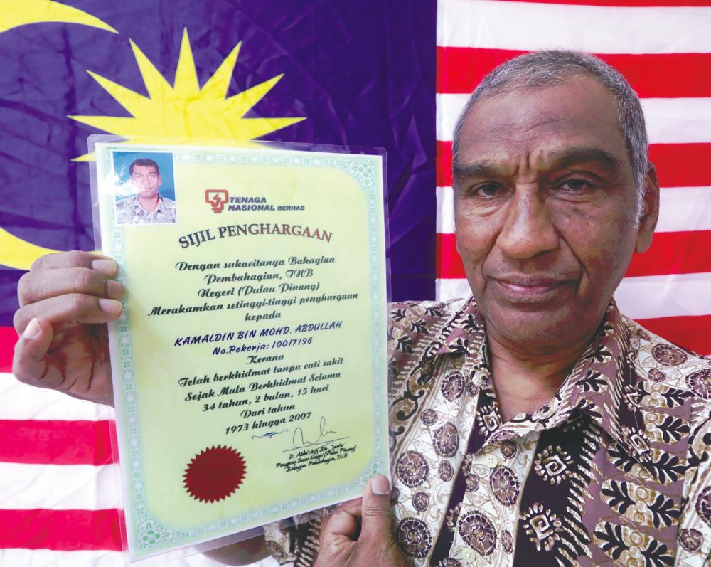 Kamaldin showing his certificate of appreciation from TNB for working 34 years without taking medical leave. – MASRY CHE ANI/THESUN