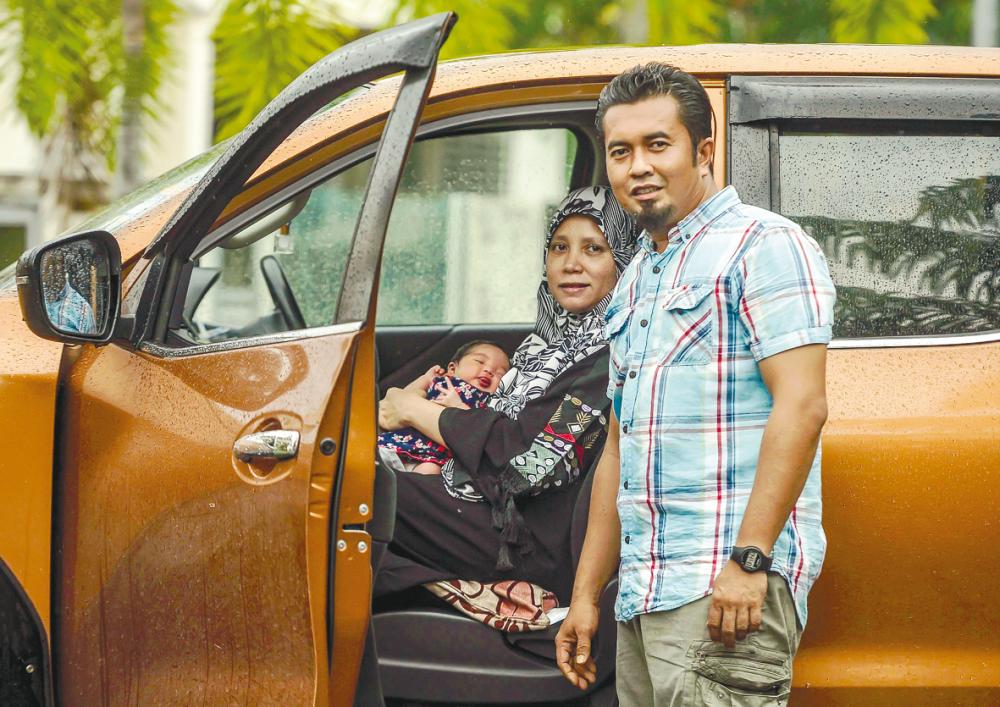 Lidawati and Ismaidi with their baby girl and the pickup truck that served as a ‘delivery room’. – ADIB RAWI YAHYA/THESUN