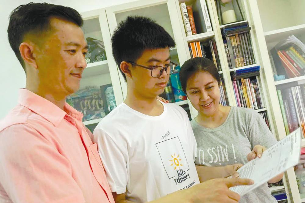 Kai Jie going through his IGCSE results with his parents. – AMIRUL SYAFIQ/THESUN