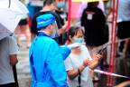 A medical worker speaks with a woman as residents and tourists queue to undergo nucleic acid tests for the Covid-19 coronavirus in Sanya in China’s southern Hainan province/AFPPix