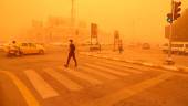 A pedestrian crosses a road in the city of Nasiriyah in Iraq’s southern Dhi Qar province on May 16, 2022 amidst a heavy dust storm. AFPPIX