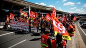 FILE PHOTO: Paris-Charles de Gaulle airport employees on strike hold French CGT labour union flags as they walk outside the Terminal 2F during a protest against low wages as inflation hits France, at the Paris-Charles de Gaulle airport in Roissy, near Paris, France, July 1, 2022. REUTERSpix