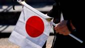 A mourner holds a Japanese national flag with a black ribbon attached to it as they pay their respects, near Nippon Budokan Hall, which will host a state funeral for former Prime Minister Shinzo Abe, in Tokyo, Japan September 27, 2022. REUTERSPIX