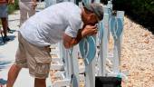 SURFSIDE, FLORIDA - JUNE 24: Michael Szochet kisses a heart setup in a memorial with the names of people that died when the 12-story Champlain Towers South condo building collapsed during the one year Surfside Remembrance Event on June 24, 2022 in Surfside, Florida. AFPPIX
