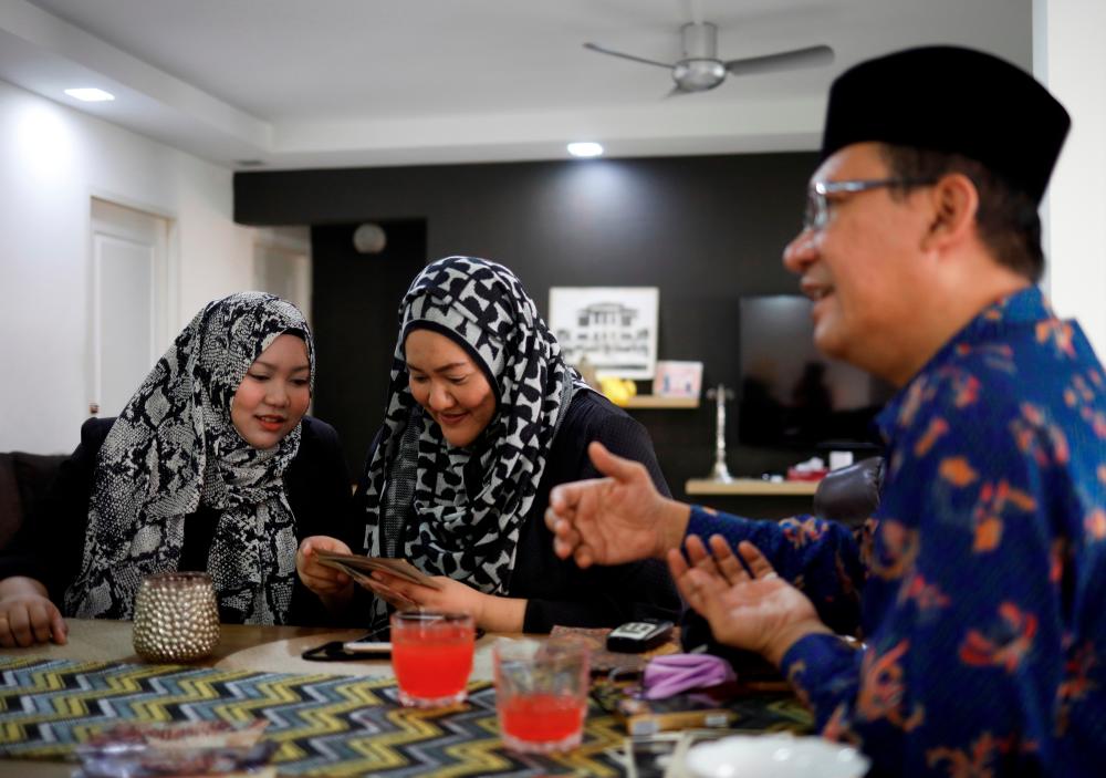 Tengku Shawal, a royal descendant, talks as his daughter Tengku Puteri (L) and his sister Tengku Intan (C) reminisce over old family photos at Intan’s home in Singapore August 21, 2020. Picture taken August 21, 2020. REUTERS/Edgar Su