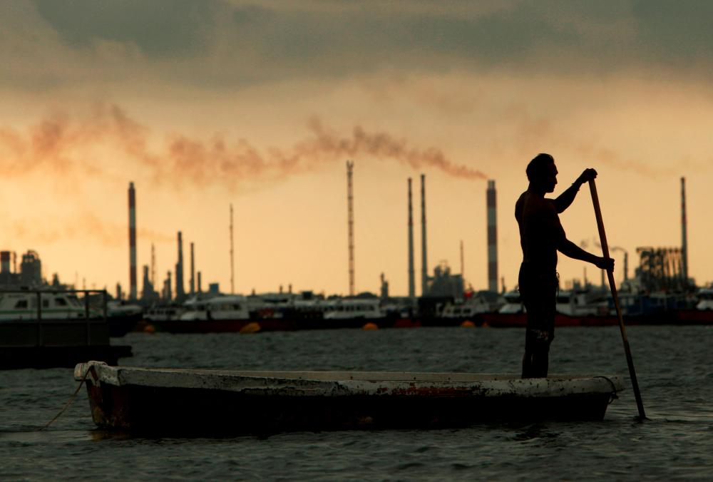 FILE PHOTO: A fisherman rows his dinghy past oil refineries near port terminals in Singapore November 5, 2013. REUTERS/Edgar Su/File Photo/File Photo