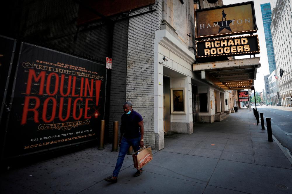 FILE PHOTO: A man walks past the shuttered Richard Rodgers Theatre, home of the popular musical “Hamilton”, in New York, U.S., July 2, 2020. REUTERS/Mike Segar/File Photo