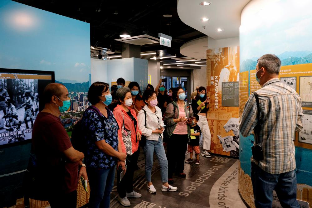 FILE PHOTO: Tourists wearing face masks listen to an instructor inside Hong Kong News-Expo during a Hong Kong Tourism Board’s free local tour, following the coronavirus disease (COVID-19) outbreak, in Hong Kong, China November 1,2020. REUTERS/Tyrone Siu/File Photo
