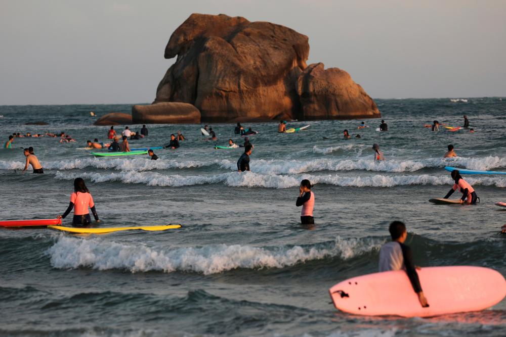 $!Surfers are seen in the sea in Sanya, Hainan province, China November 26, 2020. Picture taken November 26, 2020. REUTERS/Tingshu Wang