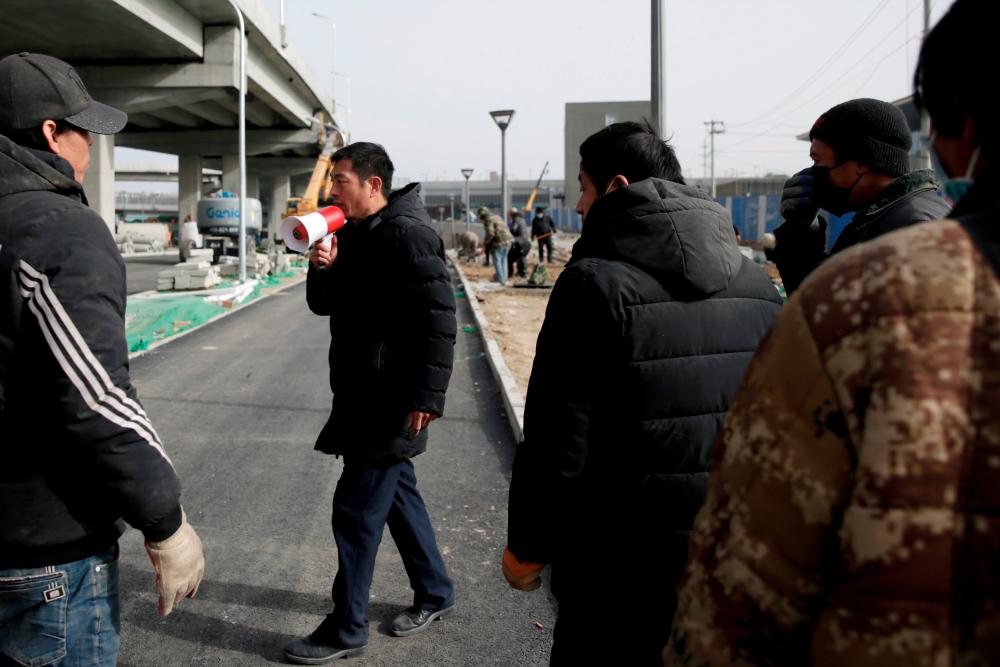 A man speaks through a loudspeaker as he directs workers to move to a different site, at a construction site, following the coronavirus disease (COVID-19) outbreak, in Beijing, China January 13, 2021. Picture taken January 13, 2021. REUTERS/Tingshu Wang