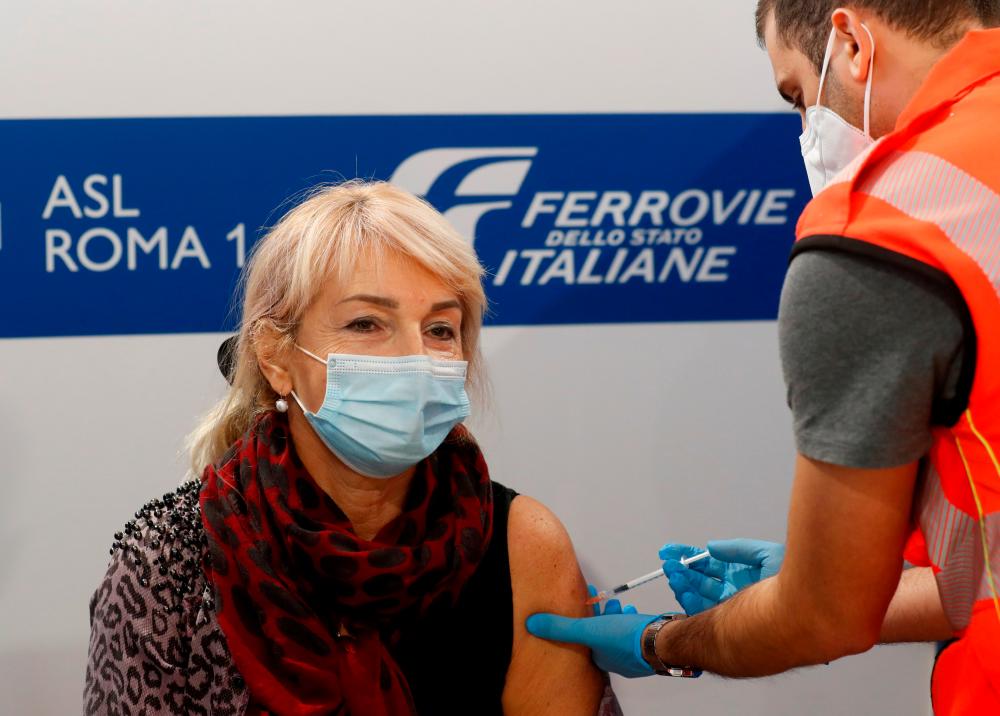 FILE PHOTO: A woman receives her third dose of coronavirus disease (COVID-19) vaccine at a Red Cross vaccination centre by Termini, Rome's main train station, as the government discusses more stringent rules for the health pass known as a Green Pass, in Rome, Italy November 24, 2021. REUTERSpix
