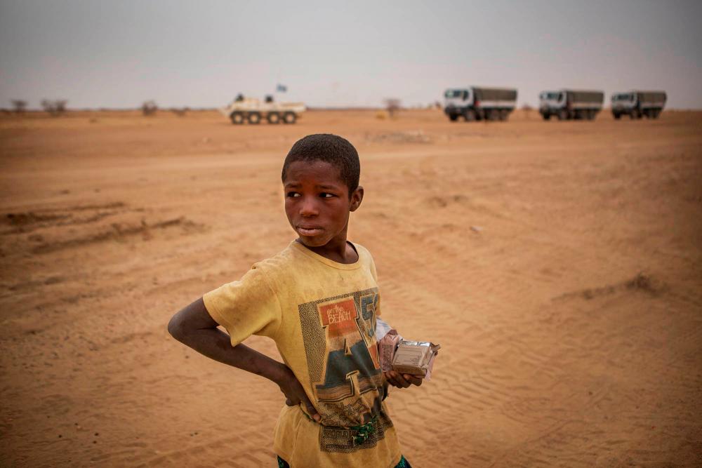FILE PHOTO: A local boy stands as a MINUSMA convoy pass by in the Gao region, Mali February 15, 2017. Each month MINUSMA organizes logistic convoys involving hundreds of civilians and military vehicles to supply remote UN bases in northern Mali. REUTERSpix