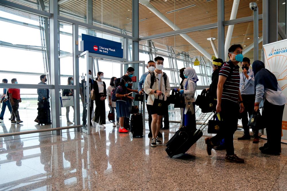 FILE PHOTO: Travellers arrive at Kuala Lumpur International Airport (KLIA) under Malaysia-Singapore Vaccinated Travel Lane (VTL) programme, after travel between the two countries was halted due to the coronavirus disease (COVID-19) pandemic, in Sepang, Malaysia November 29, 2021. REUTERSpix