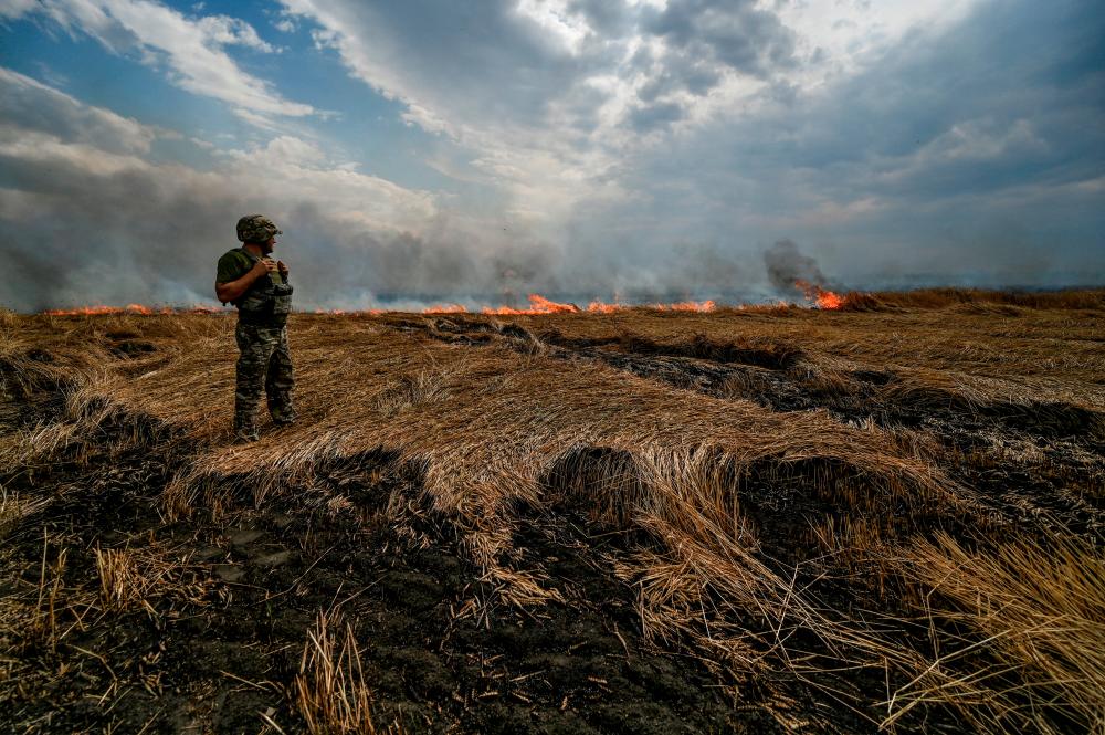 FILE PHOTO: A Ukrainian serviceman stands on a burning wheat field near a frontline on a border between Zaporizhzhia and Donetsk regions, as Russia’s attack on Ukraine continues. REUTERSPIX
