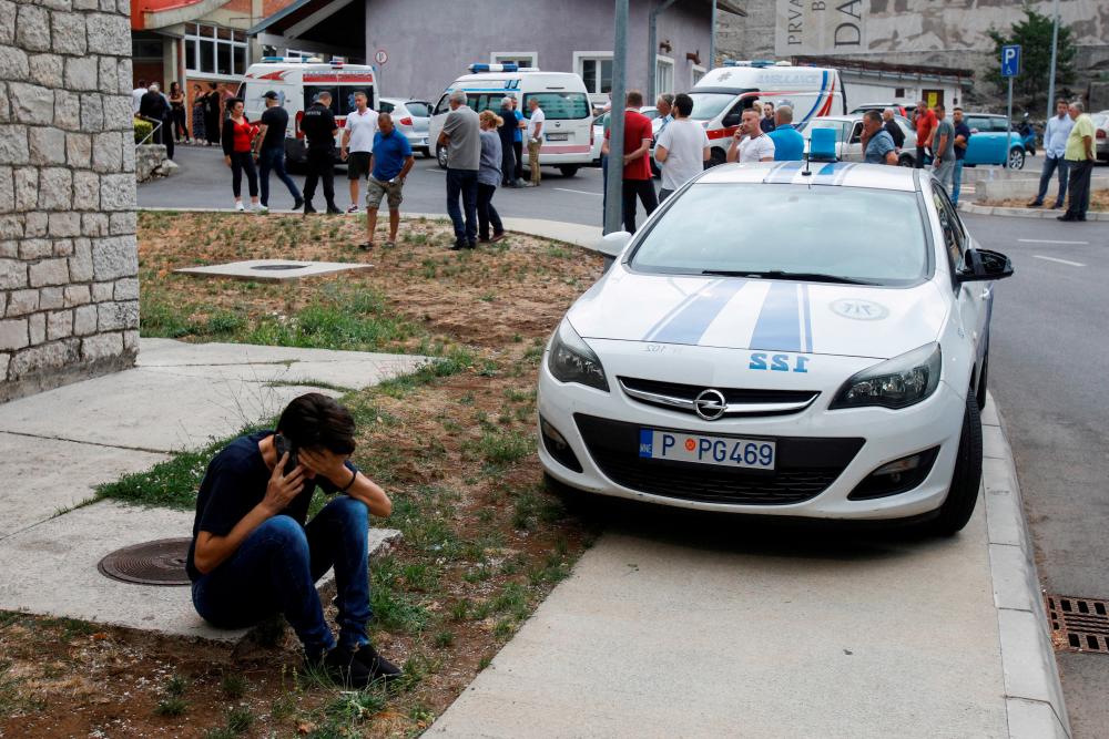 A relative of a victim talks on the phone in front of a city hospital after a mass shooting, in Cetinje, Montenegro/REUTERSPix