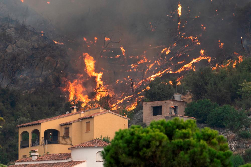 A wildfire burns behind houses near Pego, Spain, August 16, 2022. REUTERSPIX