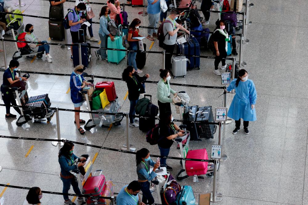 FILE PHOTO: Travellers queue up for shuttle bus to quarantine hotels at the Hong Kong International Airport, amid the coronavirus disease (COVID-19) pandemic, in Hong Kong, China, August 1, 2022. - REUTERSPIX