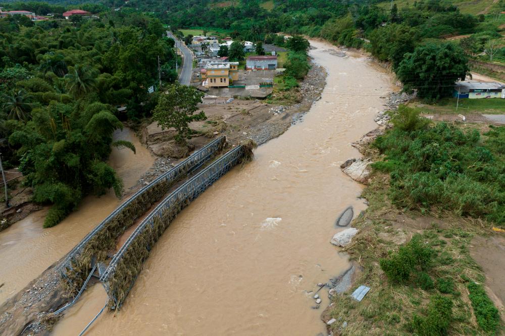 Parts of the steel bridge that was washed away are seen on the banks of the Vivi River in the aftermath of Hurricane Fiona in Utuado, Puerto Rico September 20, 2022. - REUTERSPIX