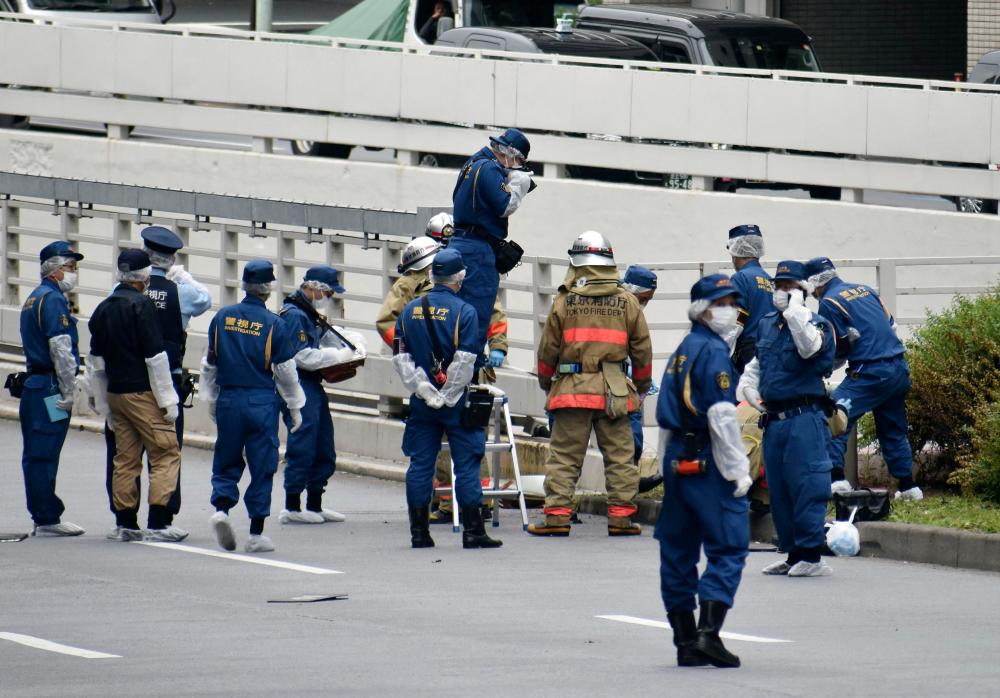 Police officers and firefighters investigate at the site where a man who was protesting a state funeral for former Japanese Prime Minister Shinzo Abe set himself on fire, near Prime Minster Fumio Kishida's official residence in Tokyo, Japan September 21, 2022 - REUTERSPIX