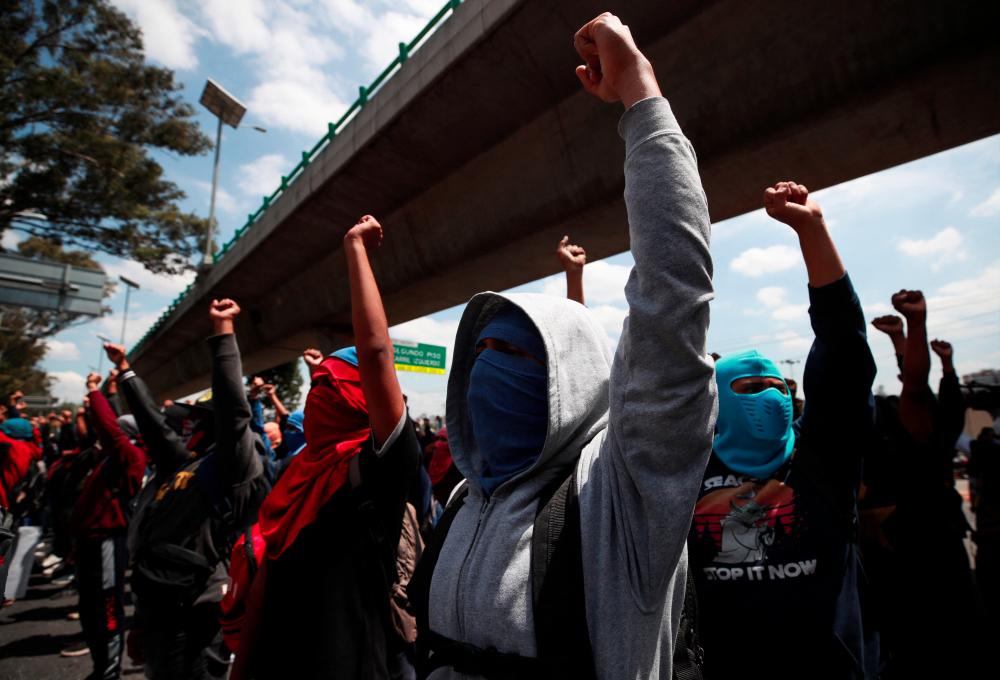 Demonstrators raise their fists during a protest ahead of the 8th anniversary of the disappearance of 43 students from Ayotzinapa Teacher Training College, outside the Campo Militar No. 1, in Mexico City, Mexico September 23, 2022. - REUTERSPIX