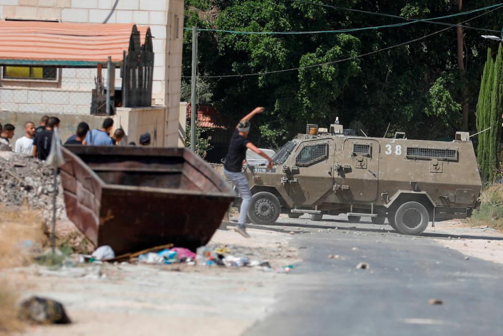 A Palestinian hurls a stone at an Israeli army vehicle during clashes after Israeli forces killed Palestinian gunmen in a raid, in Jenin in the Israeli-occupied West Bank September 28, 2022. REUTERSPIX