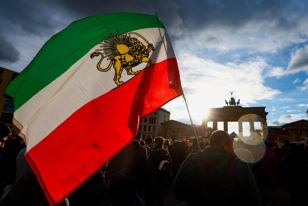 A man holds a flag during a protest following the death of Mahsa Amini in Iran, in front of the Brandenburg Gate, in Berlin, Germany, September 28, 2022. REUTERSPIX