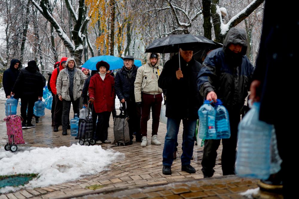 Local residents stand in line to fill up bottles with fresh drinking water after critical civil infrastructure was hit by Russian missile attacks in Kyiv, Ukraine November 24, 2022. REUTERSPIX