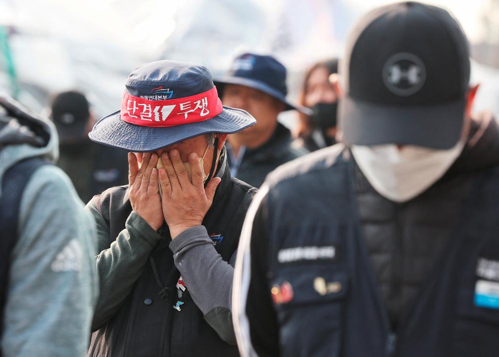 A trucker wipes his tear after the truckers union decides to end a nationwide strike at a terminal of an ICD (Inland Container Depot) in Uiwang, south of Seoul, South Korea December 9, 2022. REUTERSPIX