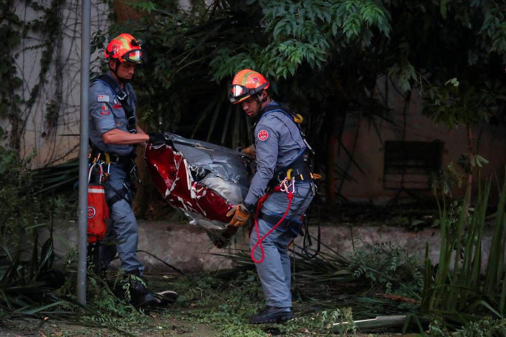 Firefighters carry parts of a helicopter after it crashed in Sao Paulo, killing 4 people according to the authorities, in Sao Paulo, Brazil, March 17, 2023. - REUTERSPIX
