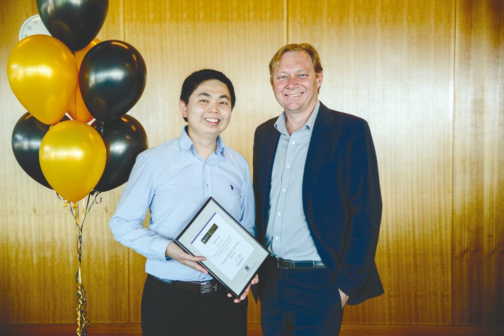 Tan receiving the award for teaching excellence from University of Queensland Executive Dean of the Faculty of Business, Economics and Law, Prof Andrew Griffiths.