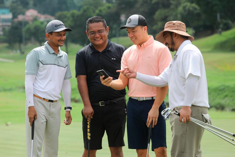NEVER GOLF ALONE... Wong (second from right) checking out the golf app with his friends. - ASYRAF RASID/THESUN