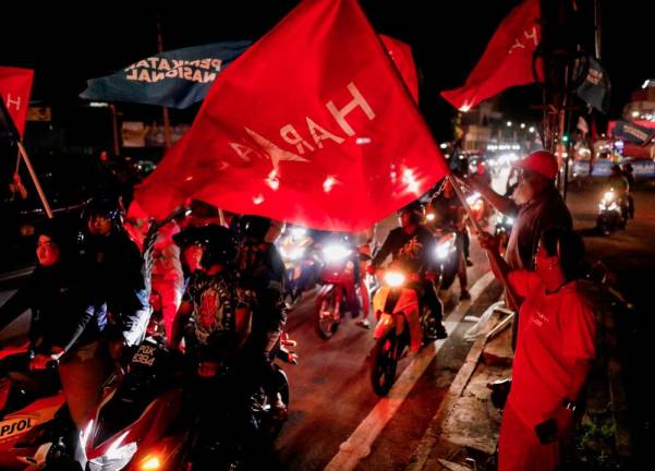 Pakatan Harapan supporters waves the party flag to the motorists on the eve of Malaysia's general election at Butterworth, Penang, Malaysia November 18, 2022. - REUTERSPIX