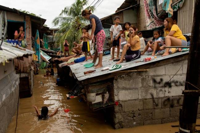 Residents wait on the roof of their homes, for flooding to subside after Super Typhoon Noru, in San Miguel, Bulacan province, Philippines/REUTERSPix