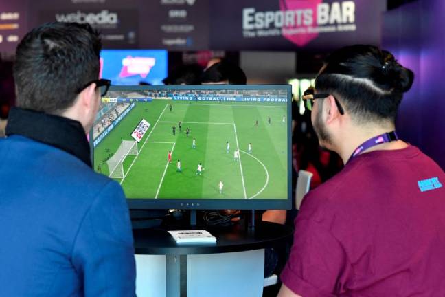 (FILES) This file photo taken on February 13, 2019, shows visitors playing on EA Vancouver video game developer's football simulation video game FIFA 19 at the eSports Bar trade fair in Cannes, southern France. - AFPPIX
