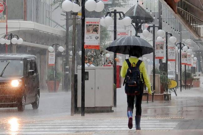A pedestrian crosses the street during a downpour in the centre of Shizuoka, Shizuoka prefecture on the south coast of Japan on August 13, 2022, as heavy rains brought by Tropical Storm Meari hit the area/AFPPix