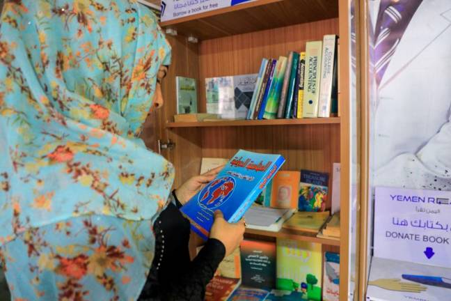 A Yemeni woman checks out a book from a mini-library, put in place by “Yemen Reads” campaign, in the capital Sanaa on September 29, 2020. / AFP / Mohammed HUWAIS