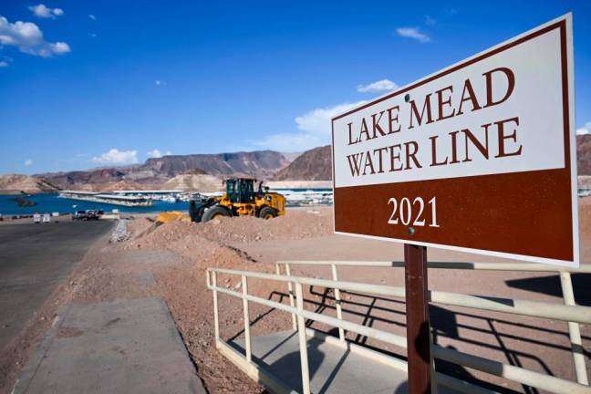A sign indicates the Lake Mead water line in 2021 in contrast to current low water levels as construction equipment stands nearby to expand the boat launch ramp due to the western drought on June 28, 2022 on Lake Mead along the Colorado River in Boulder City/AFPPix