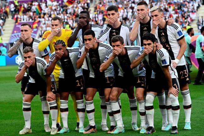 Players of Germany cover their mouths as they pose for the group picture ahead of the Qatar 2022 World Cup Group E football match between Germany and Japan at the Khalifa International Stadium in Doha on November 23, 2022. - AFPPIX