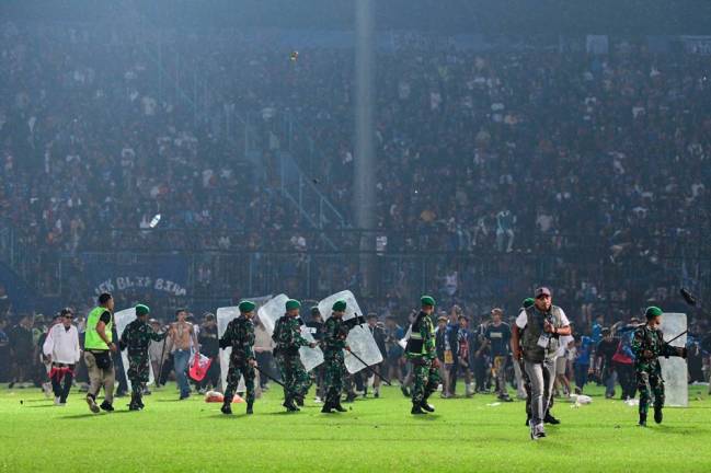 This picture taken on October 1, 2022 shows members of the Indonesian army securing the pitch after a football match between Arema FC and Persebaya Surabaya at Kanjuruhan stadium in Malang, East Java/AFPpix