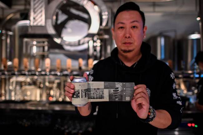 This photo taken on November 20, 2020 shows Wang Fan, founder of the No. 18 Brewery, posing with one of his beers with images of the city’s fight against the Covid-19 coronavirus in Wuhan, China’s central Hubei province. AFP / Hector RETAMAL