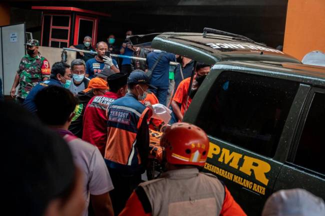 Medical workers receive a body at a hospital in Malang, East Java on October 2, 2022. At least 174 people died at an Indonesian football stadium when thousands of angry home fans invaded the pitch and police responded with tear gas that triggered a stampede, authorities said on October 2. - AFPPIX