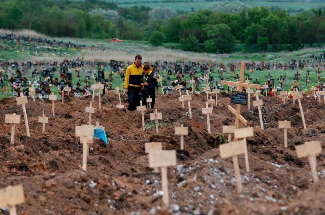 People stand amid newly-made graves at a cemetery in the course of Ukraine-Russia conflict in the settlement of Staryi Krym outside Mariupol/REUTERSPix