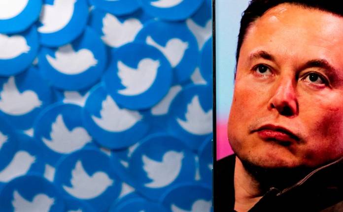 An image of Musk is seen on a smartphone placed on printed Twitter logos in this picture illustration. REUTERSpix