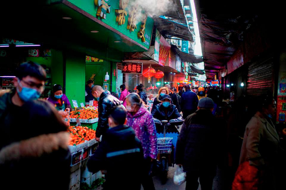 People wearing face masks walk on a street market, following an outbreak of the coronavirus disease (Covid-19) in Wuhan, Hubei province, China February 8, 2021. REUTERSPIX