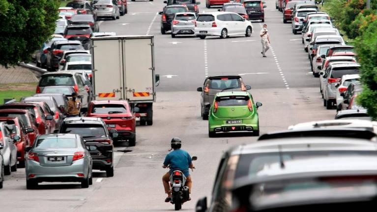 Shortage of spaces for cars at Serdang Hospital forces visitors to haphazardly park their vehicles on the road. – HAFIZ SOHAIMI/THESUN
