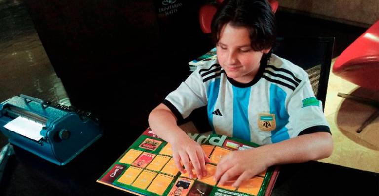 Sebastian Filoramo, 12, a visually impaired boy who adapted the FIFA World Cup Qatar 2022 Panini card album to Braille, checks his album in Barquisimeto, Venezuela. – REUTERSPIX