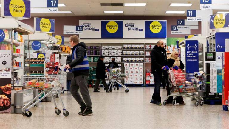 Shoppers walk next to the clubcard price branding inside a branch of a Tesco Extra Supermarket in London, Britain, February 10, 2022. Picture taken February 10, 2022. REUTERSPIX