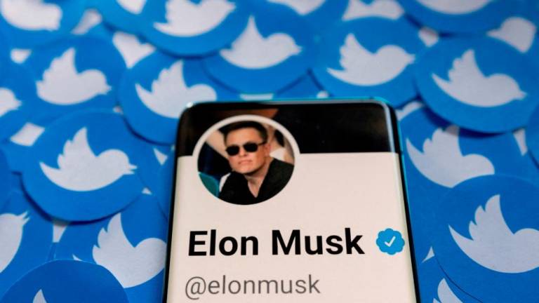 Musk’s Twitter profile is seen on a smartphone placed on printed Twitter logos in this picture illustration. – Reuterspic